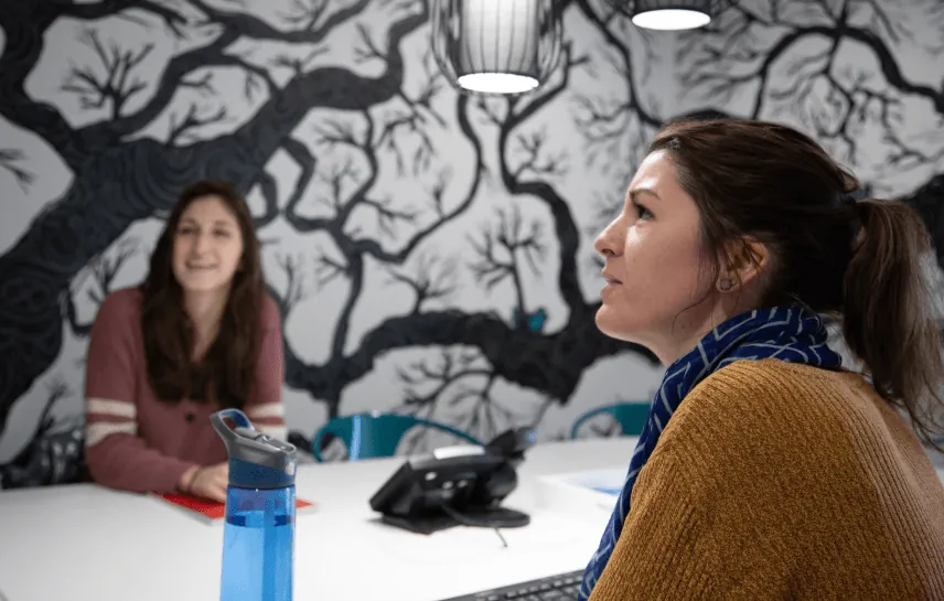 a woman sits at a table with a blue water bottle in front of her